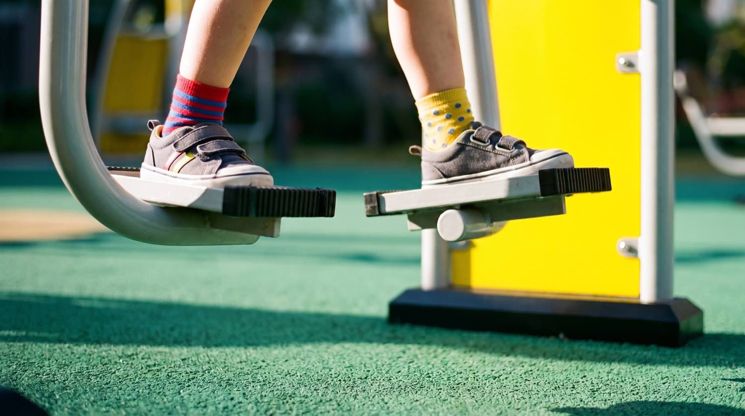 Gros plan sur les pieds d'un enfant sur les pédales d'un appareil de fitness Herkules