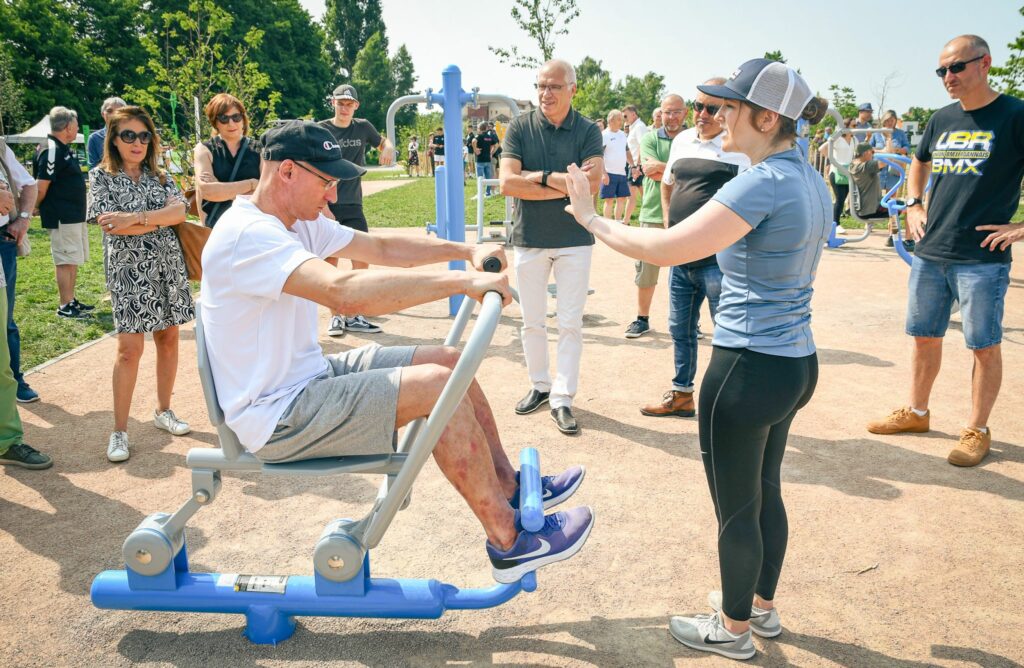 Adulte pratiquant le fitness en plein air sur des équipements extérieurs. Dynamisation de la vie étudiante par le sport en extérieur.