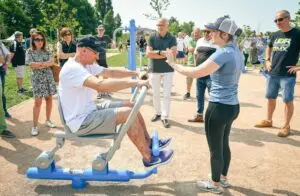 Adulte pratiquant le fitness en plein air sur des équipements extérieurs. Dynamisation de la vie étudiante par le sport en extérieur.